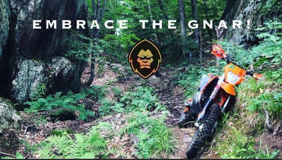Enduro motorcycle on a forest trail with Embrace the Gnar text and the MÖTÖX head mark